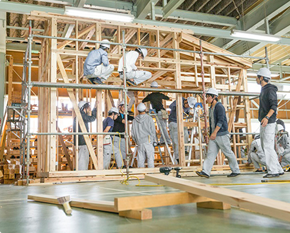 屋内実習場で住宅を建てる学生